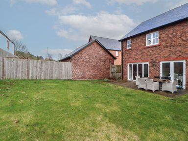 A backyard with green grass a wooden fence a brick house with patio furniture at 4 Centurion Rise in Penrith