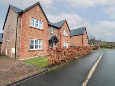 A street view of brick houses with a hedge and paved driveway at 4 Centurion Rise in Penrith