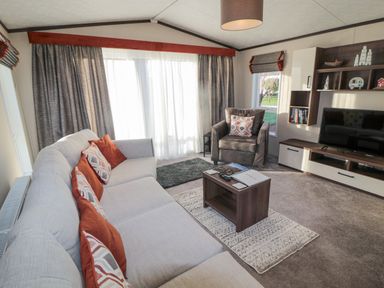 A living room with a sofa and armchair a coffee table and a television at Downtime Lodge near Felton