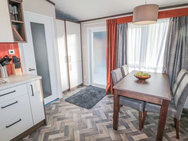 A kitchen and dining area with a table and four chairs next to a window with curtains at Downtime Lodge near Felton