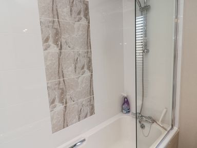 A bathtub with a mounted shower head and a spray bottle of shower cleaner at Downtime Lodge near Felton