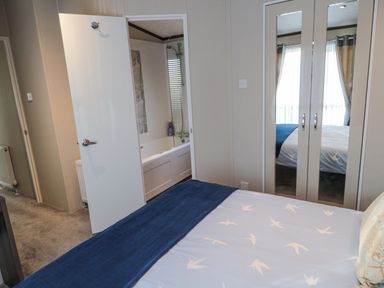 A bedroom with a bed a mirrored wardrobe and a bathroom visible through an open door at Downtime Lodge near Felton