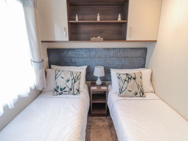A bedroom with two single beds a nightstand with a lamp and decorative pillows at Downtime Lodge near Felton