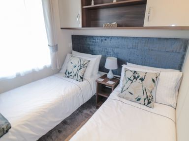 A bedroom with two single beds a nightstand with a lamp and floral pillows at Downtime Lodge near Felton