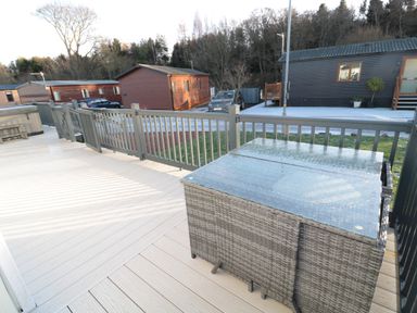 A deck with a glass top table and chairs and nearby mobile homes at Downtime Lodge near Felton