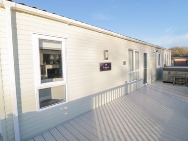 A light-colored exterior wall with windows and a door on a wooden deck at Downtime Lodge near Felton