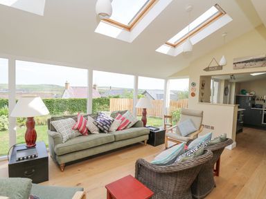 A living room with sofas armchairs side tables and lamps at Tree Tops in Newport Pembrokeshire
