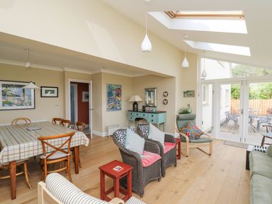A living and dining area with wicker chairs and a dining table at Tree Tops in Newport Pembrokeshire