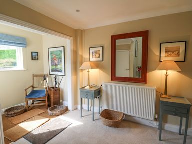 A hallway with two side tables with lamps a large mirror a wooden chair and wicker baskets at Tree Tops in Newport Pembrokeshire