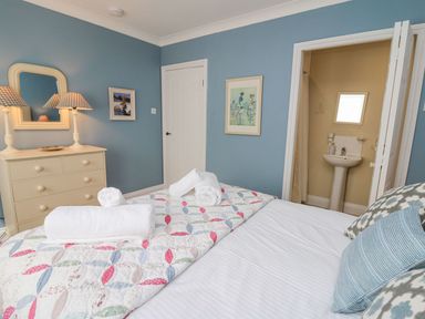 A bedroom with a bed with pillows and towels a dresser with lamps and mirror and an ensuite bathroom at Tree Tops in Newport Pembrokeshire