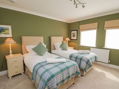 A bedroom with two single beds and side tables with lamps at Tree Tops in Newport Pembrokeshire