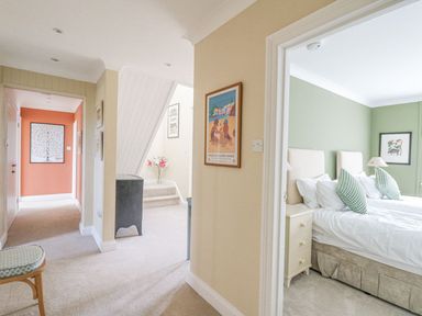 A hallway with armchair stairs and a bedroom with two single beds and green walls at Tree Tops in Newport Pembrokeshire