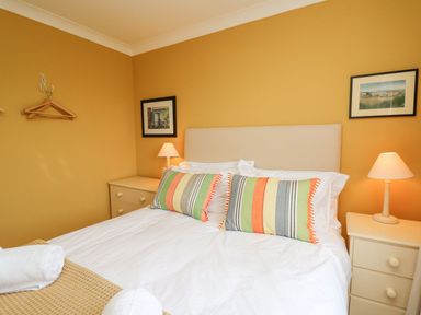 A bedroom with a double bed two striped pillows and bedside tables with lamps at Tree Tops Newport Pembrokeshire