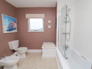 A bathroom with a toilet bidet bathtub window and padded storage bench at Tree Tops in Newport Pembrokeshire