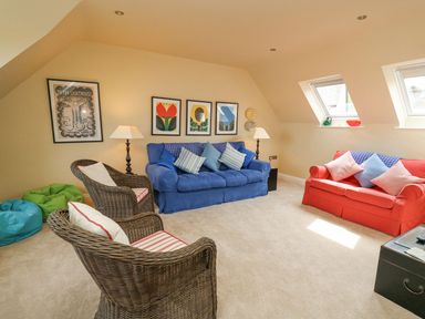 A living room with two sofas two wicker chairs bean bags and artwork on the walls at Tree Tops in Newport Pembrokeshire