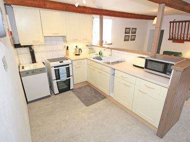 A kitchen with cream cabinets oven microwave and toaster at Y Stabl The Old Stable in Llanbedr