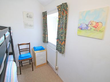 A small bedroom with bunk beds a wooden chair and a small dresser with towels at Y Stabl The Old Stable in Llanbedr