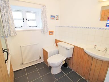 A bathroom with a toilet sink radiator and window at Y Stabl The Old Stable in Llanbedr