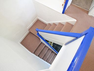 A carpeted staircase with blue railings and white walls at The Farmhouse in Llanbedr