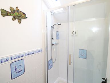 A shower room with tiled walls and a fish decoration at The Farmhouse in Llanbedr