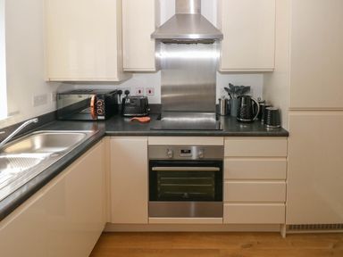 A kitchen with a stainless steel oven a microwave a toaster a kettle and utensils on the countertop at Ty Bach Twt Llanelli