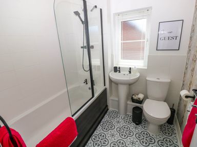 A bathroom with a bathtub shower combination a sink and a toilet at Ty Bach Twt Llanelli