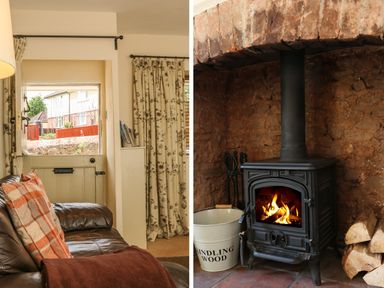 A brown leather sofa with cushions near a half door and floral curtains and a wood burning stove with a bucket labeled kindling wood and firewood at Little Dragons in Dunster near Minehead