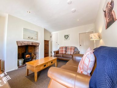 A living room with two leather sofas a wooden coffee table a fireplace and a lamp at Little Dragons in Dunster near Minehead