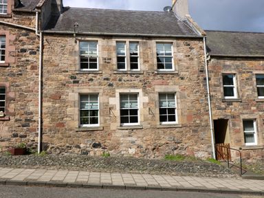Stone exterior of a building with six windows and a small gate at 49 Castlegate in Jedburgh