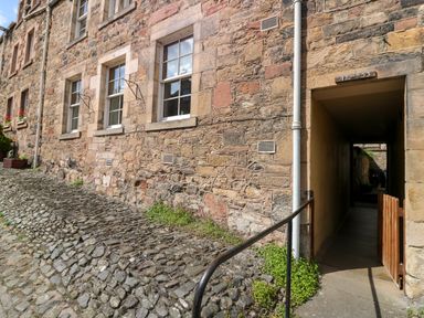 A stone building with windows and a passageway alongside a cobblestone path at 49 Castlegate in Jedburgh