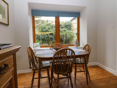 A dining area with a wooden table and four chairs near a window showing a garden at 49 Castlegate in Jedburgh