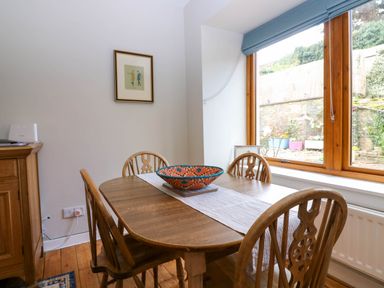A dining area with a wooden table and chairs near a window at 49 Castlegate in Jedburgh
