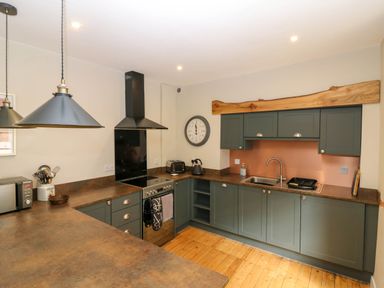 A kitchen with green cabinets wooden countertops and flooring at 49 Castlegate in Jedburgh