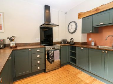 A kitchen with green cabinets wooden floor and a stove at 49 Castlegate in Jedburgh