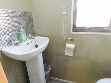 A bathroom sink with faucet and soap dispenser near a window with a roll of toilet paper at Tanyfron Holiday Caravan in Bryngwran near Gwalchmai