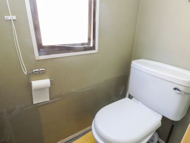 A bathroom with a white toilet a toilet paper holder and a window at Tanyfron Holiday Caravan in Bryngwran near Gwalchmai