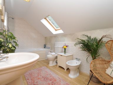A bathroom with a bathtub, sink, toilet, and chair at The Hayloft in Lostwithiel