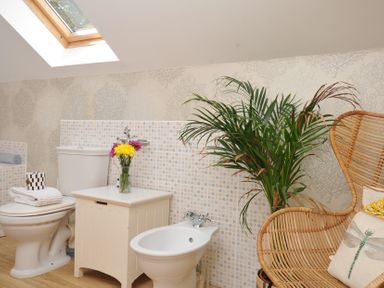 A bathroom with a toilet, bidet, sink, and chair at The Hayloft in Lostwithiel