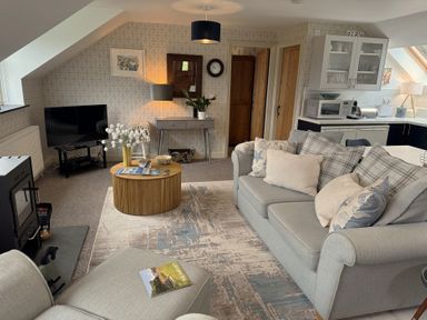 A living room with a sofa, coffee table, and television at The Hayloft in Lostwithiel