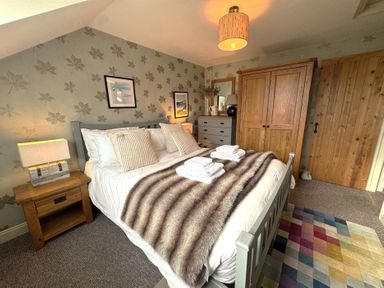 A bedroom with a bed, lamp, closet, and wall decorations at The Hayloft in Lostwithiel