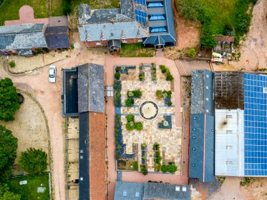 An aerial view of multiple buildings surrounding a central courtyard with a fountain and landscaping at Oak Cottage in Aylesbeare