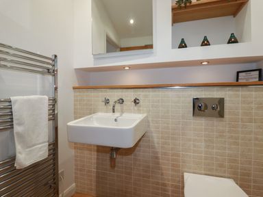 A bathroom with a wall-mounted sink heated towel rail and a toilet at 2 Miller's Island Near Lanreath