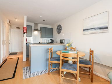 A kitchen with grey cabinets and a dining table with four chairs at Harbour Escape in Porthmadog