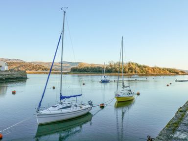 A river or harbor with sailboats moored and hills in the background at Harbour Escape in Porthmadog