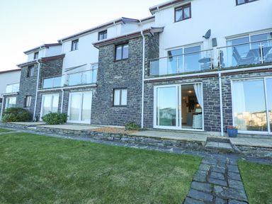 A row of terraced houses with stone and white walls and glass balcony railings at Harbour Escape in Porthmadog