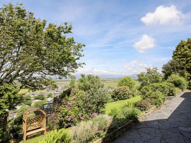 A garden with a wooden bench and various shrubs next to a stone pathway at Bryn Awelon in Harlech