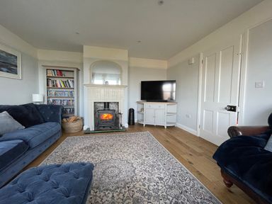 A living room with a fireplace tv bookshelf and two sofas at Bryn Awelon in Harlech