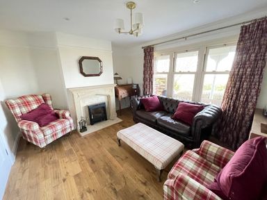 A living room with a fireplace two patterned armchairs a leather sofa and a plaid ottoman at Bryn Awelon in Harlech