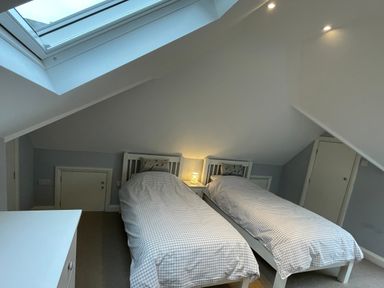 A bedroom with two single beds under a slanted ceiling and a skylight at Bryn Awelon in Harlech