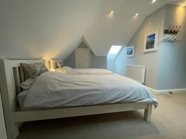 A bedroom with two single beds under a slanted ceiling near a window and framed pictures at Bryn Awelon in Harlech